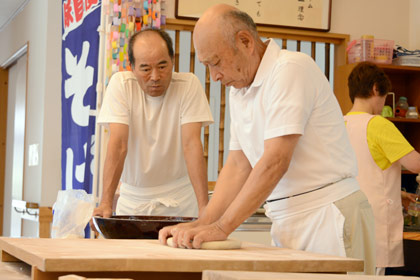職人の横では、大久保さんが須藤さんの技をじっくり拝見。師匠の技は見て盗め！次回の大久保さんの蕎麦が楽しみですね！